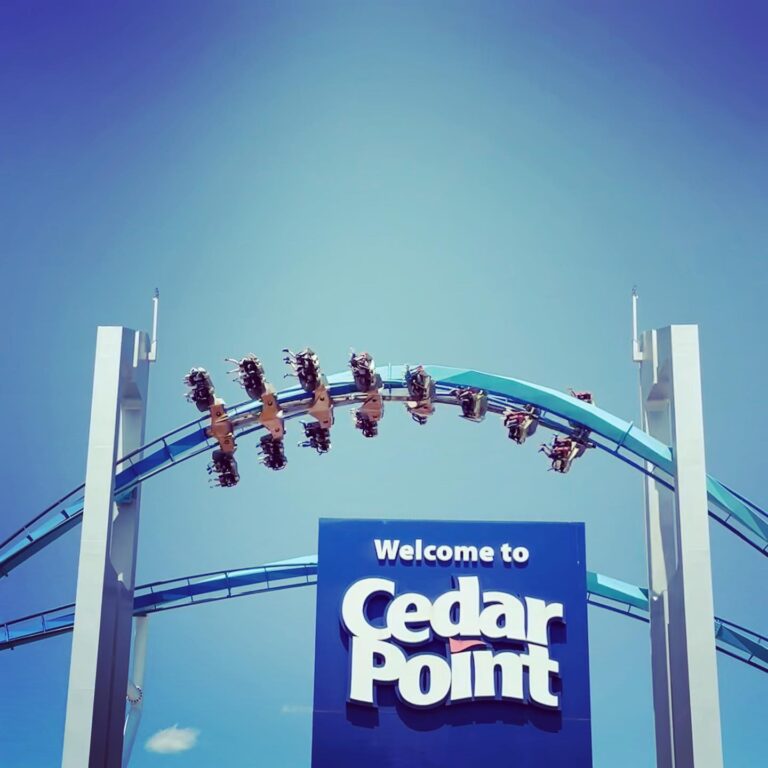 GateKeeper’s wing-coaster train flying over the Welcome to Cedar Point sign at the main entrance, 2023.