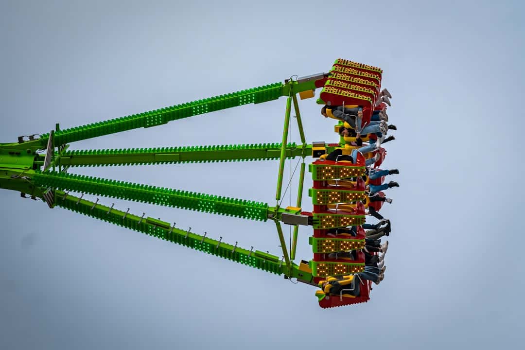 how loud are roller coasters - A green and yellow carnival ride in the sky