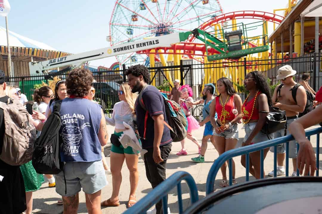 tracking roller coasters music events sporting events - People at a sunny amusement park with rides.