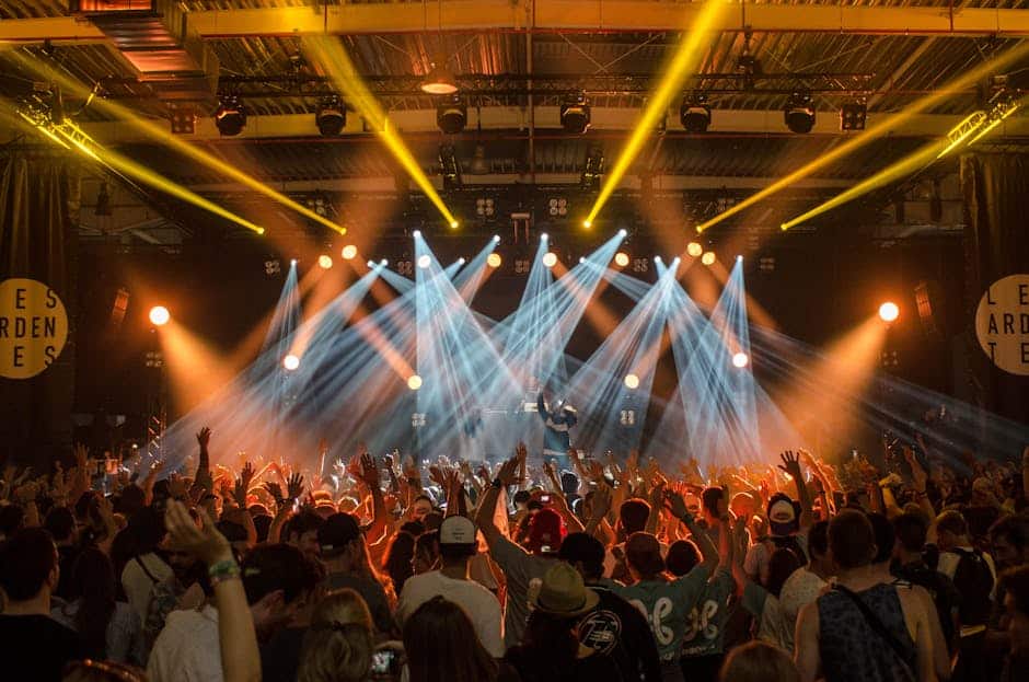 theme park news April 2026 - Energetic music concert scene with bright lights and a lively cheering crowd indoors.