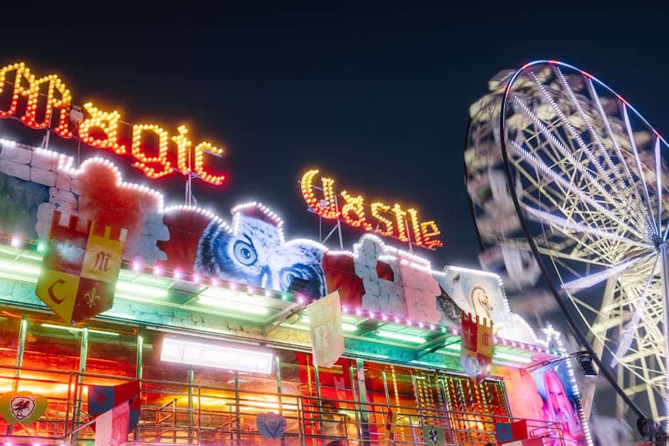 theme park news April 2026 - A lively carnival scene featuring a Ferris wheel and the colorful Magic Castle at night.