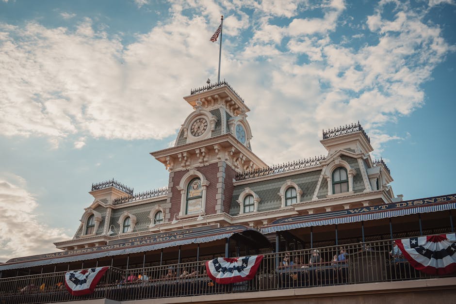 Iconic entrance to Walt Disney World Railroad at Magic Kingdom, Orlando, Florida, with vintage architecture and American flags.