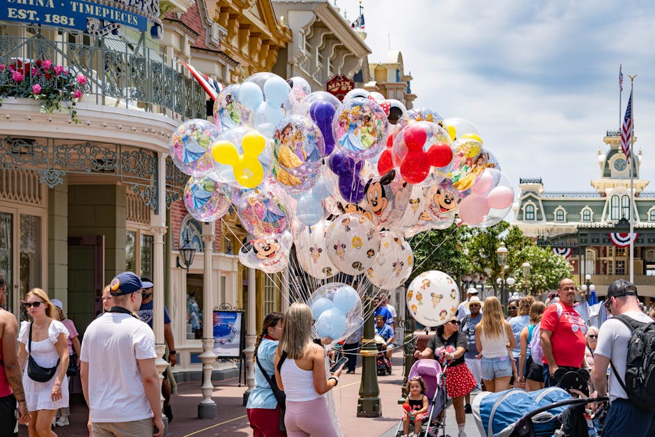 theme park off-season travel - Colorful Disney-themed balloons on Main Street, USA at Disney World, with a lively crowd enjoying a sunny day.
