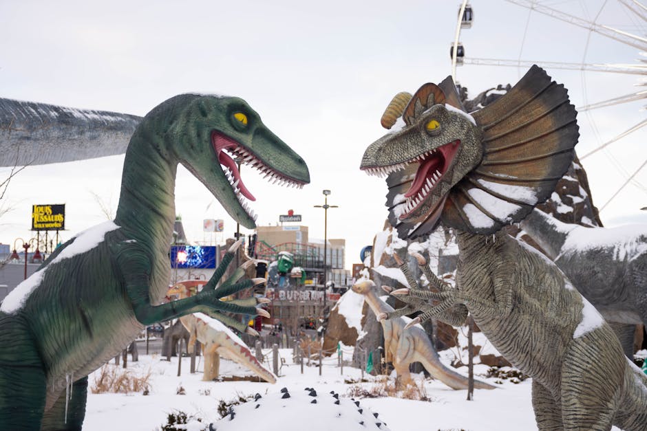 theme park off-season travel - Snow-covered dinosaur statues at a theme park, set in a winter wonderland.