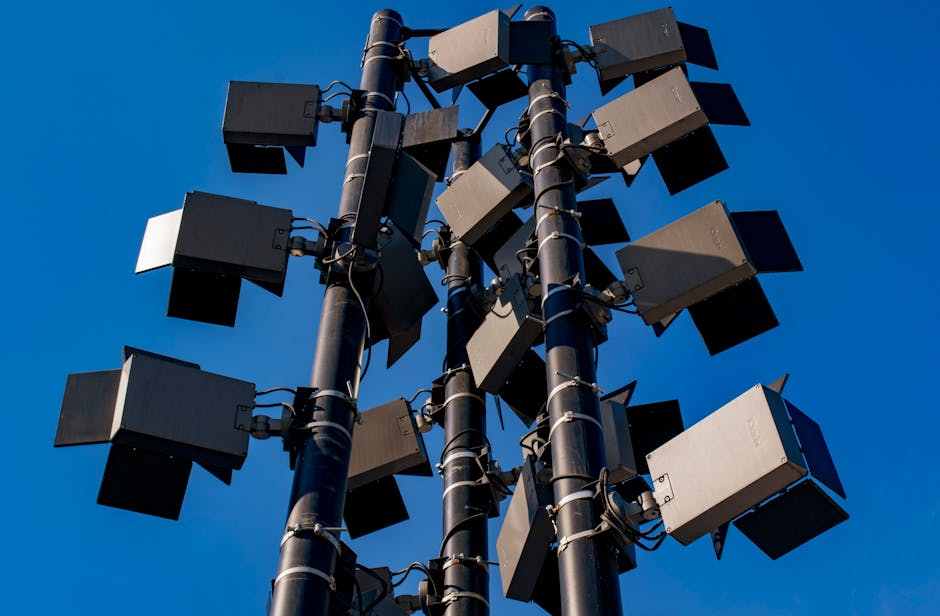 stadium tour concert - Low angle view of modern outdoor stadium floodlights against a clear blue sky.