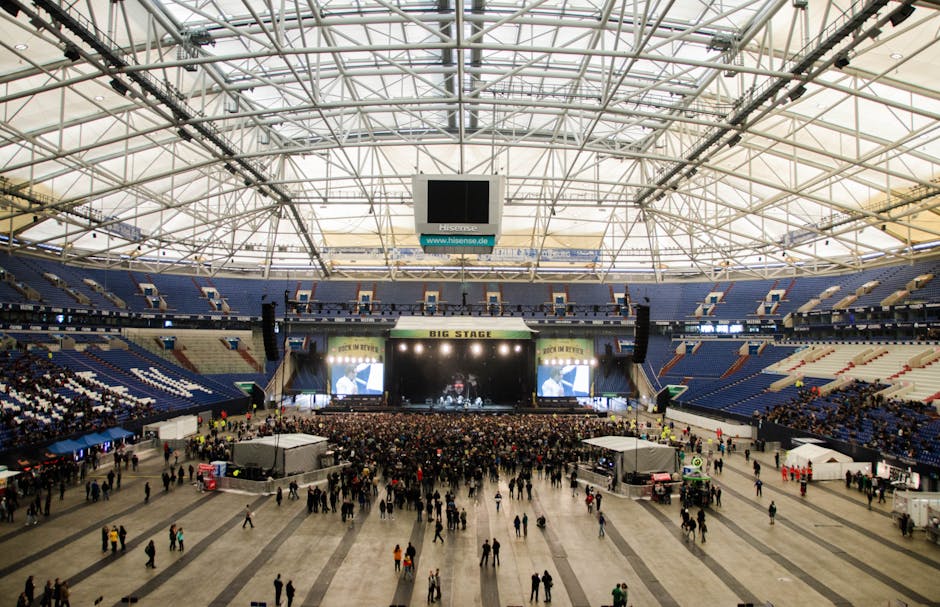 concert sound system - Wide shot of a crowded concert in a large indoor arena with a prominent stage.