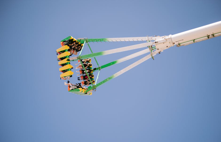 six flags magic mountain - People enjoying a thrilling amusement park ride suspended midair against a clear blue sky.