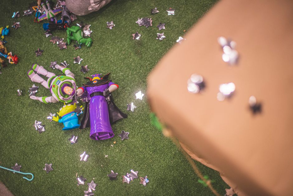 theme park news - Buzz Lightyear and Zurg toy figures on artificial grass surrounded by star-shaped decorations.