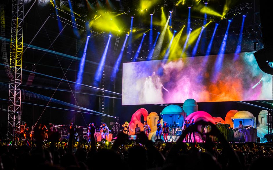 **weekly concert news** - Energetic concert scene with colorful lights and performers on stage