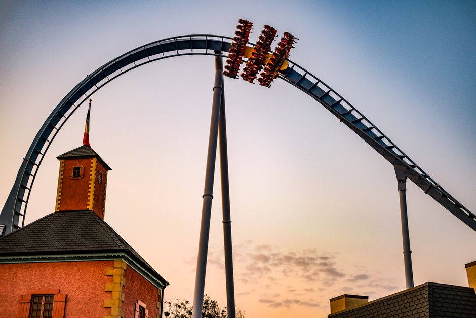 theme park news - A roller coaster loop silhouetted against a vibrant sunset sky, capturing excitement and adventure.