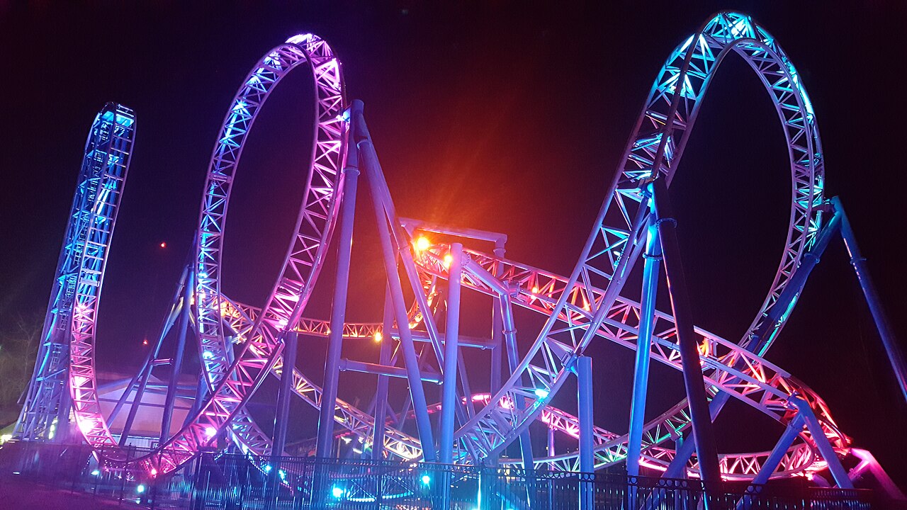 Adrenaline Peak's loop and corkscrew glowing pink and blue at night at Oaks Amusement Park