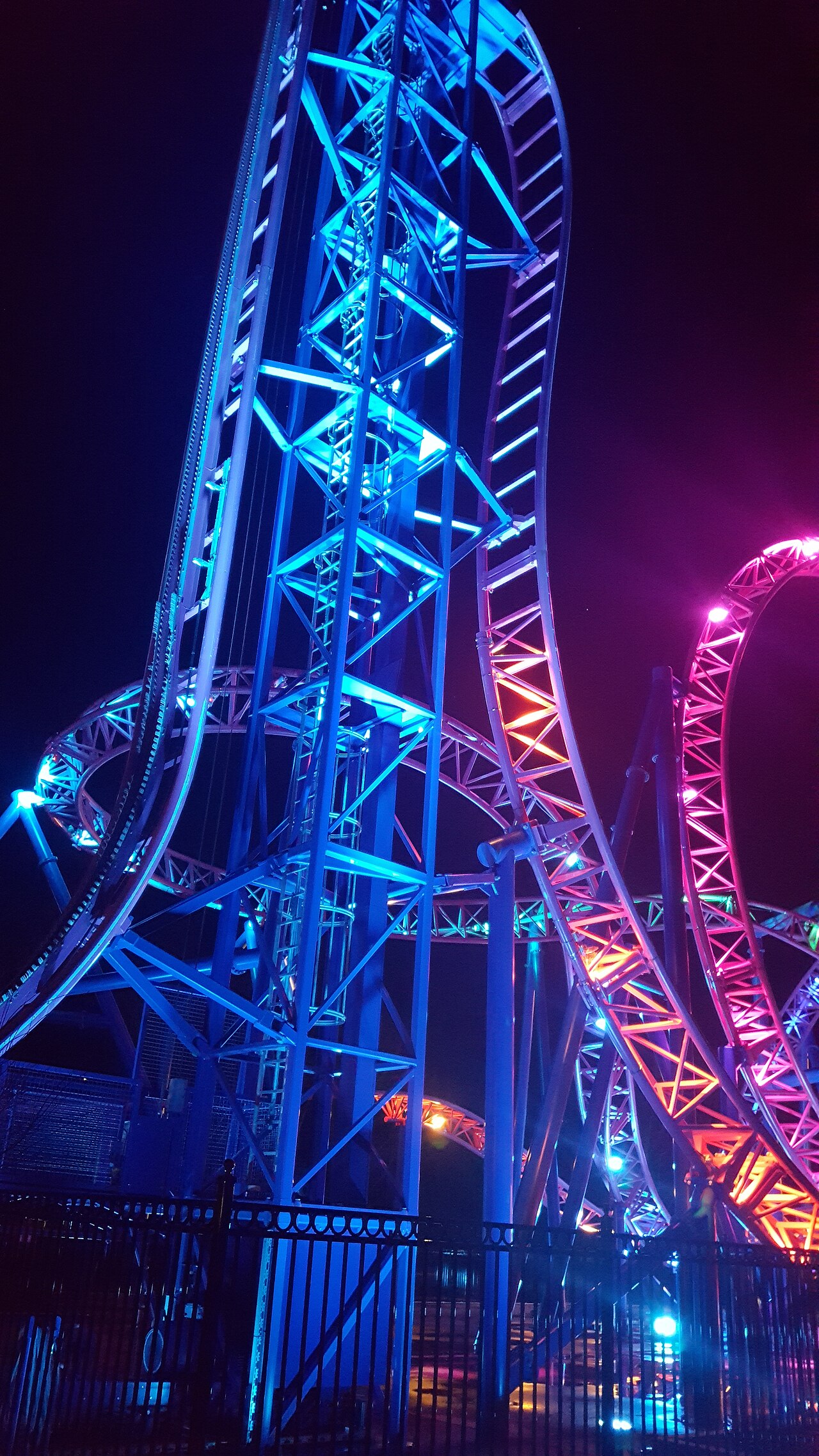 Adrenaline Peak's 90-degree vertical lift tower illuminated in blue and pink at night