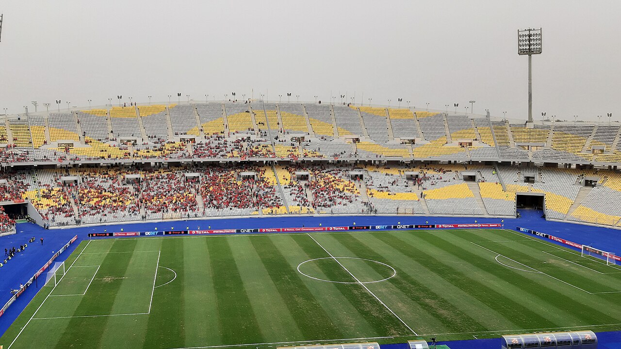 Daytime view of Borg El Arab Stadium's yellow and white seating bowl and running track
