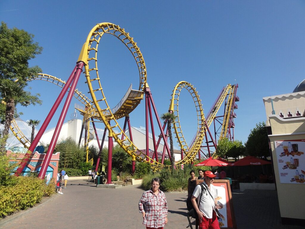 Cobra roller coaster at Walibi Belgium, a Vekoma Boomerang with yellow track and dark red supports, showing its loop and cobra roll