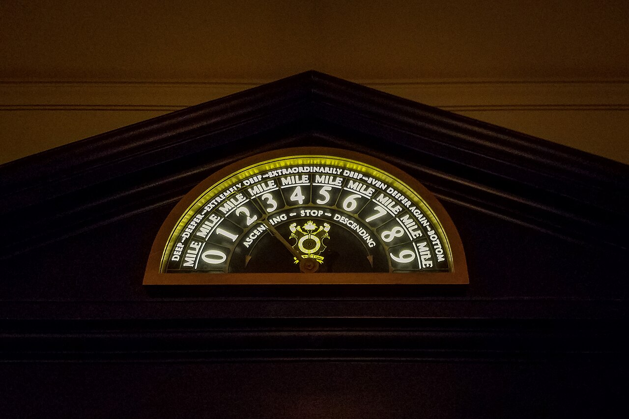 Illuminated depth gauge marked in miles above the elevator in the Escape from Gringotts queue