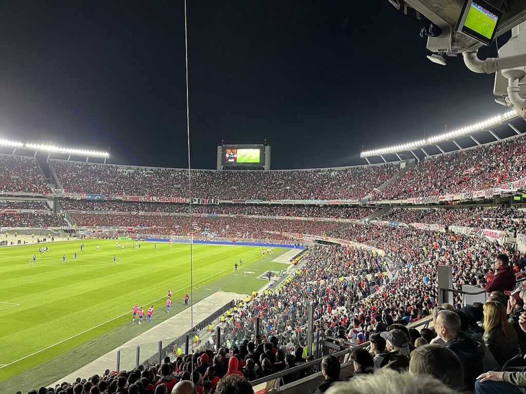 Packed Estadio Más Monumental at night in 2023, with the new lower stands built where the athletics track used to be