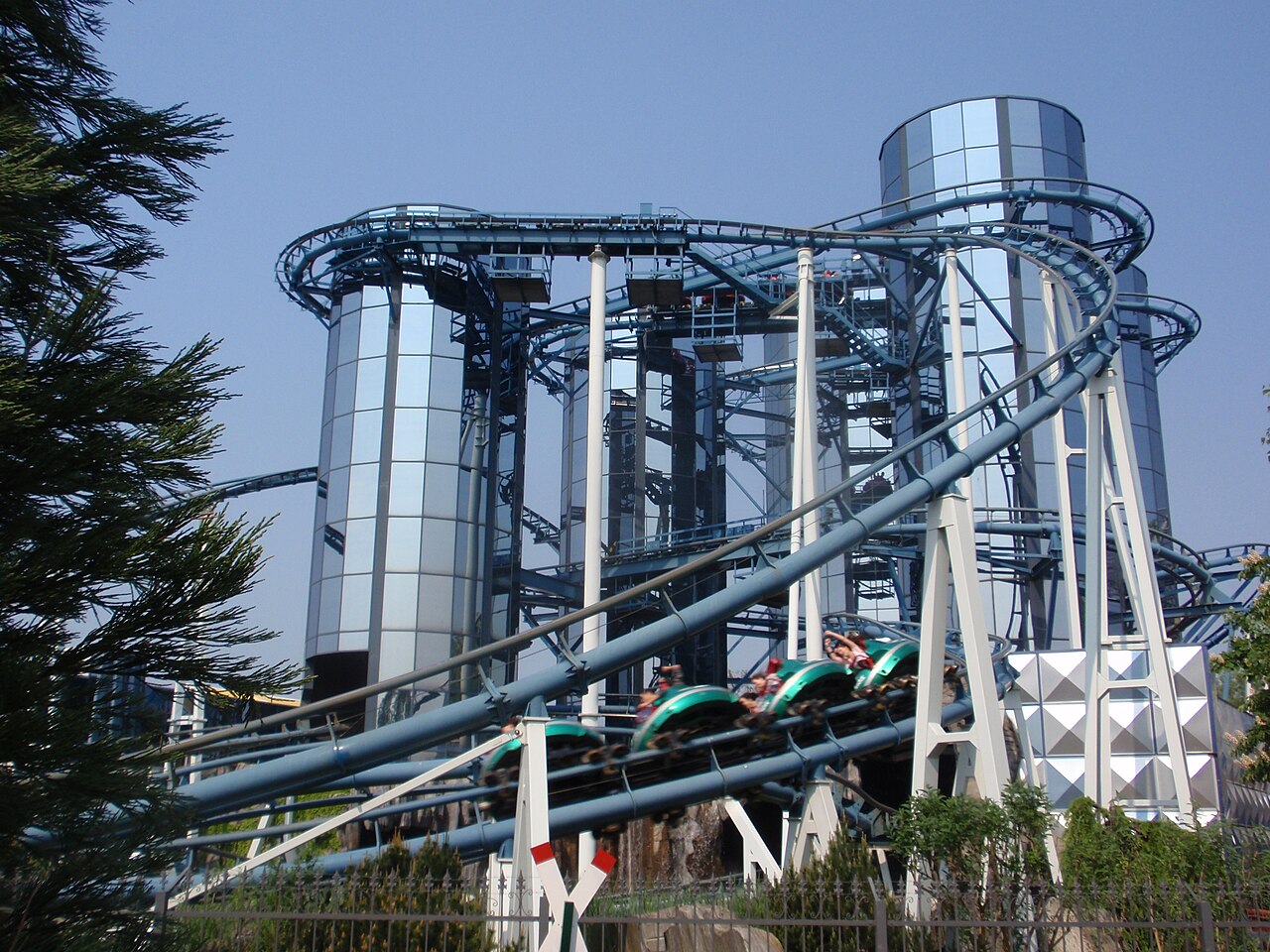 Euro-Mir train full of riders descending a drop in front of the mirrored glass towers at Europa-Park