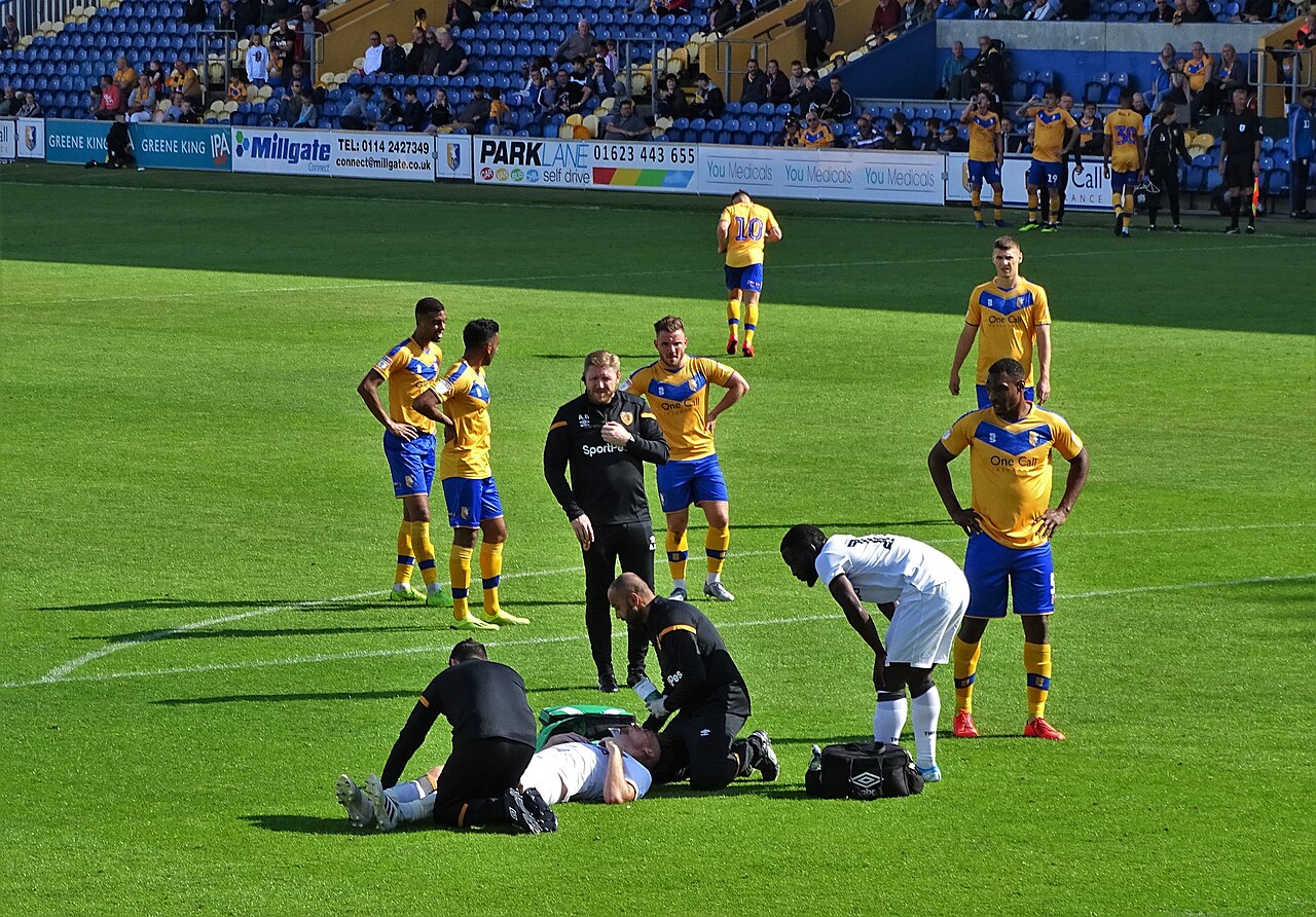 Mansfield Town players in amber and blue during a match at Field Mill