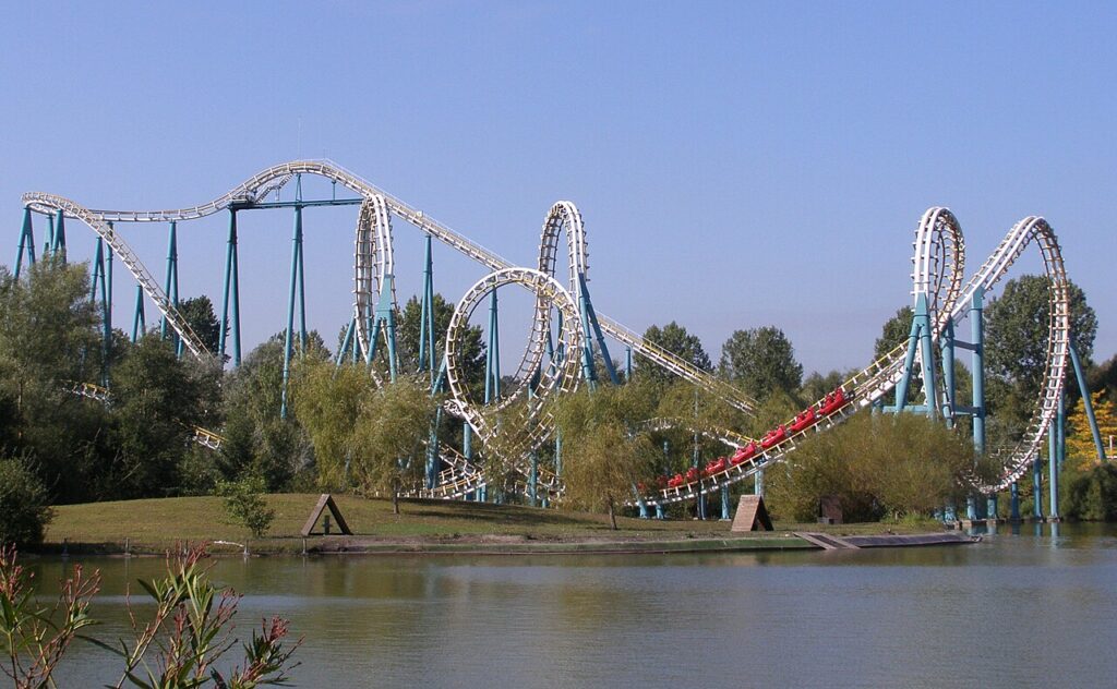 Full layout of the Goudurix roller coaster at Parc Astérix with its loops and corkscrews seen across the lake