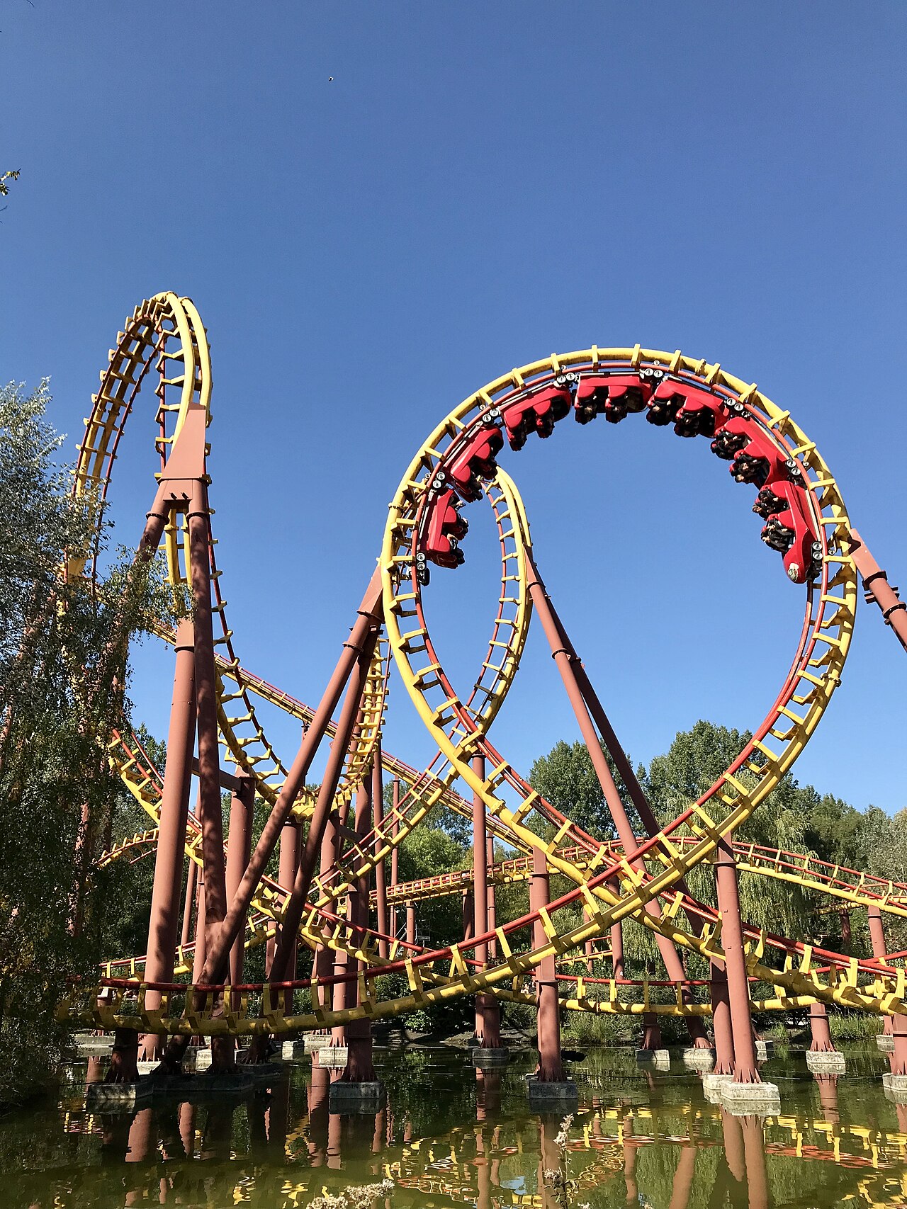 A red Goudurix train rounds the top of the vertical loop on yellow track at Parc Astérix