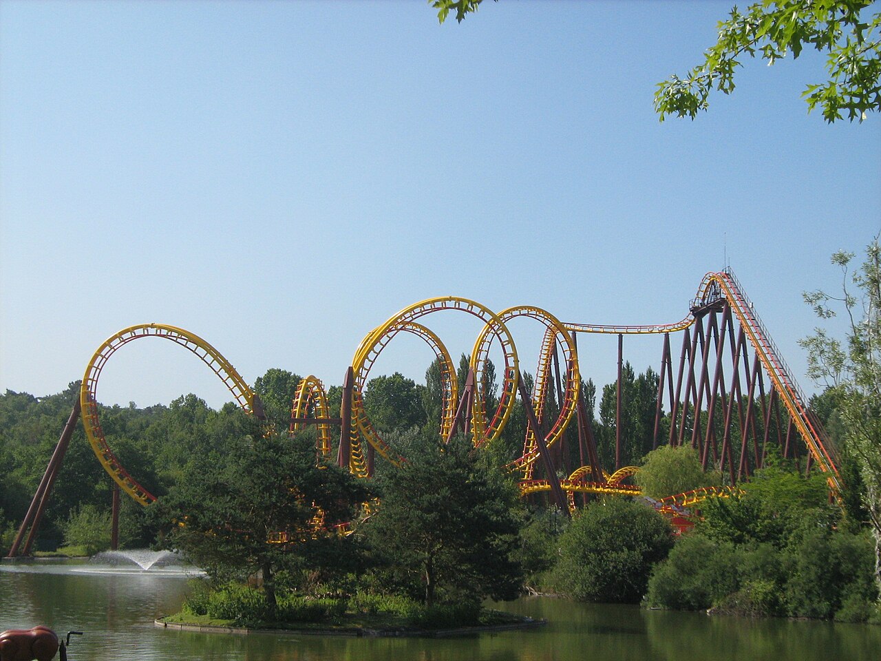Wide view of Goudurix's loops, corkscrews and lift hill above the lake at Parc Astérix