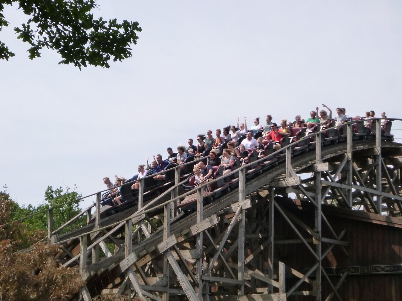 A packed Joris en de Draak train flying over the wooden camelback hills at Efteling