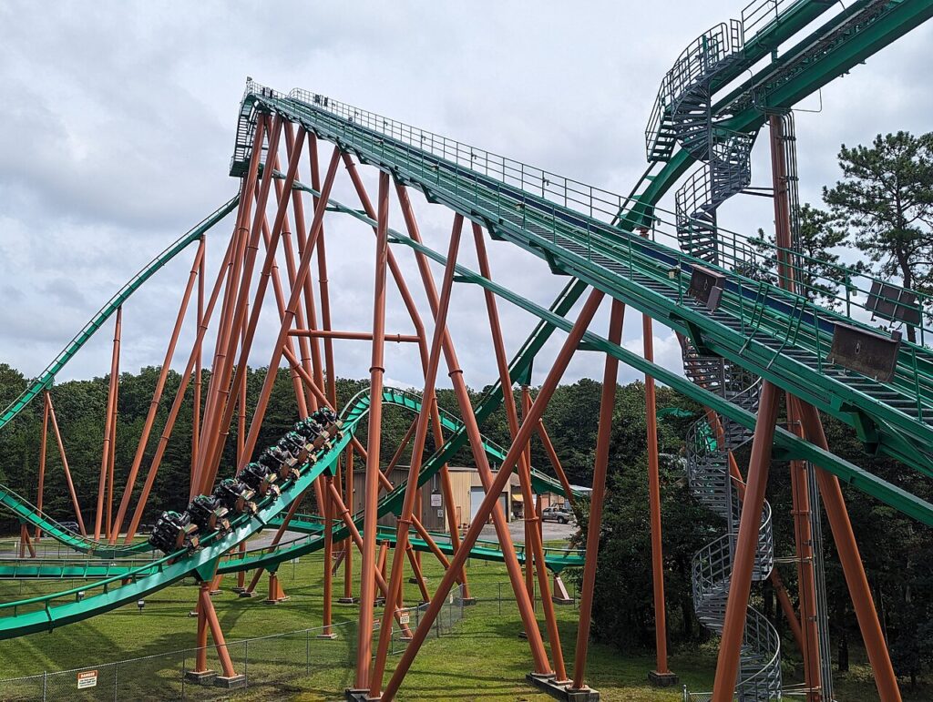 Medusa's green track and orange supports with a train diving off the lift hill at Six Flags Great Adventure