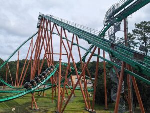 Medusa's green track and orange supports with a train diving off the lift hill at Six Flags Great Adventure