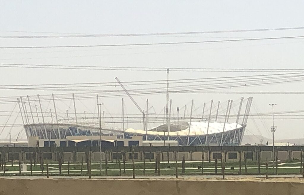 Misr Stadium in Egypt's New Administrative Capital during construction, showing its elliptical bowl and crown-like roof supports