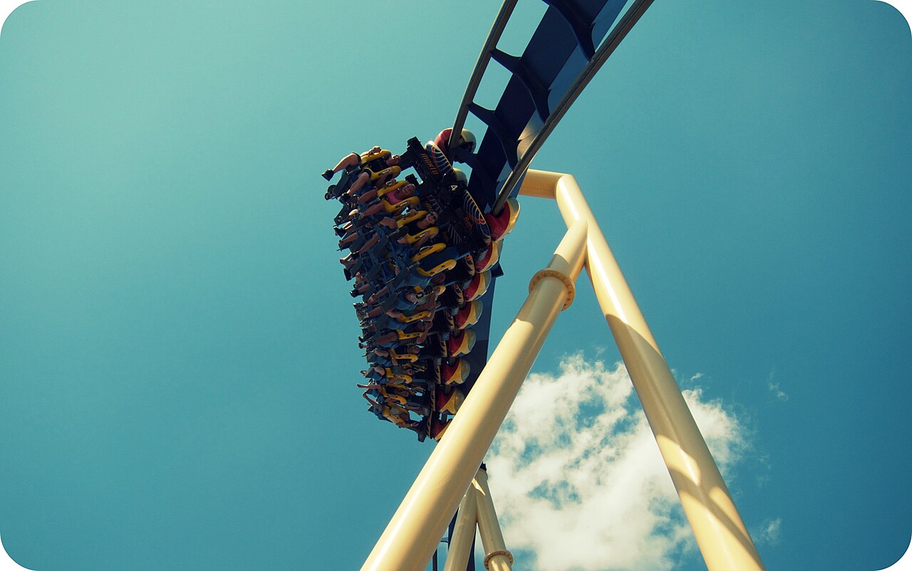 Looking up at a Montu train hanging beneath the blue track against the sky at Busch Gardens Tampa