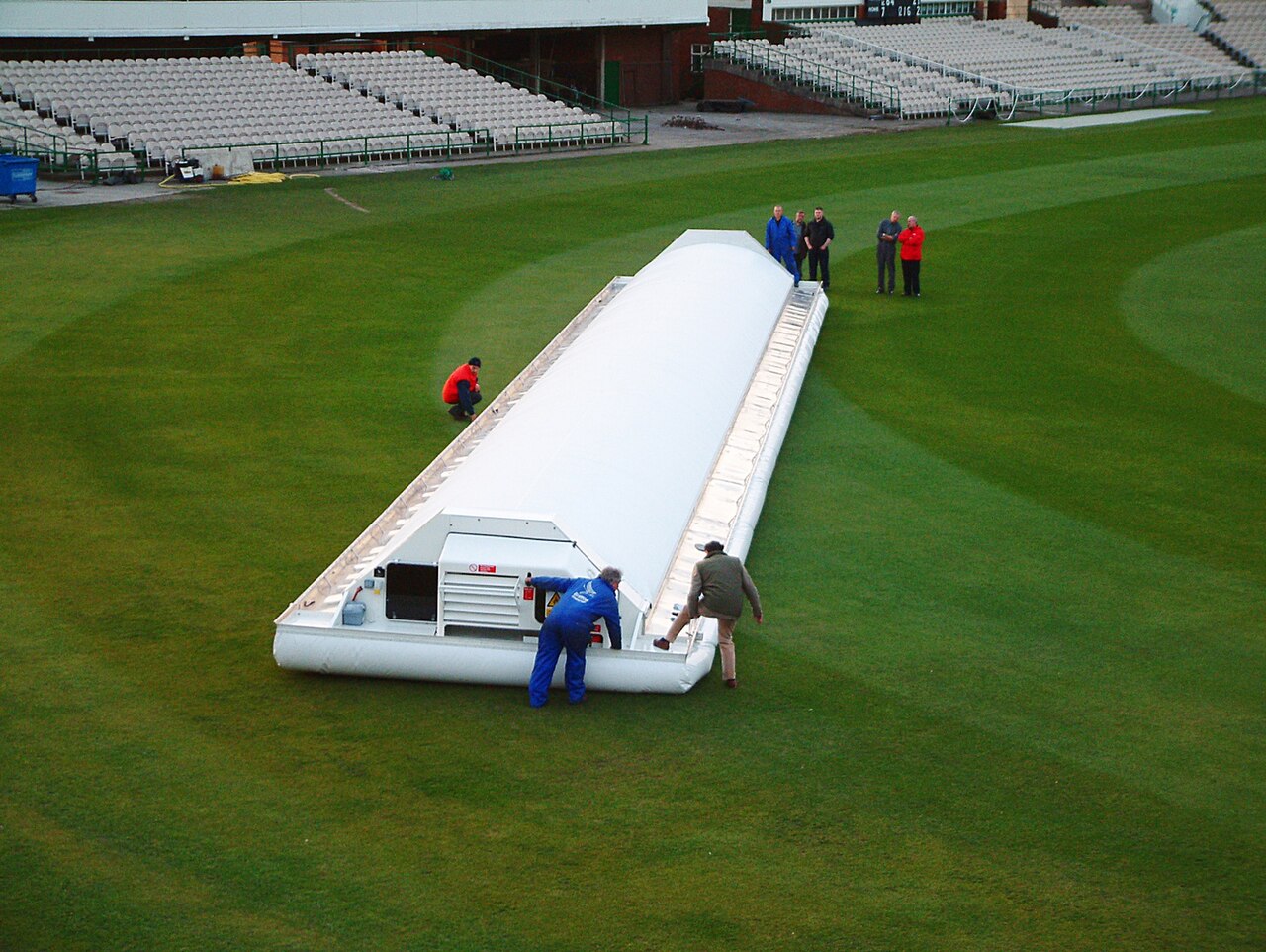 The hover cover being deployed over the pitch at Old Trafford during rain