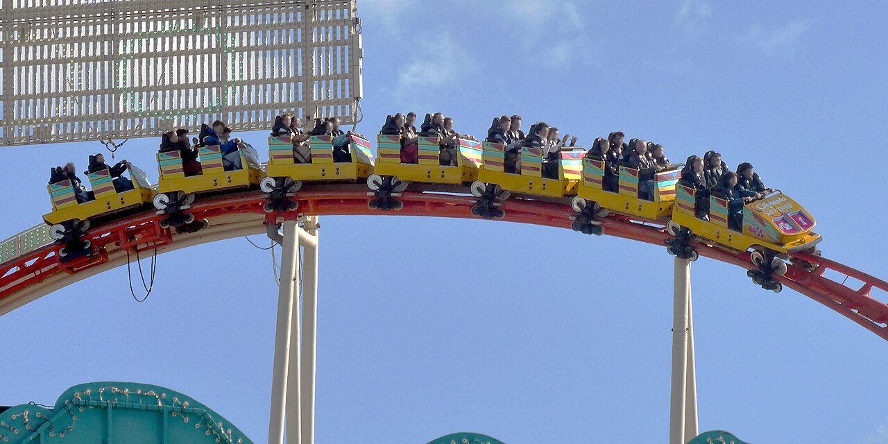 Olympia Looping train full of riders cresting a hill on the orange track at Oktoberfest in Munich