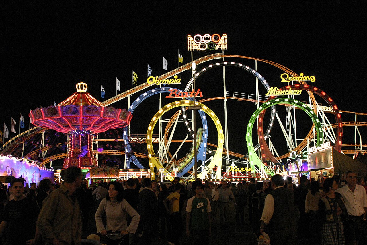 Olympia Looping's five loops outlined in colored lights at night at Oktoberfest in Munich