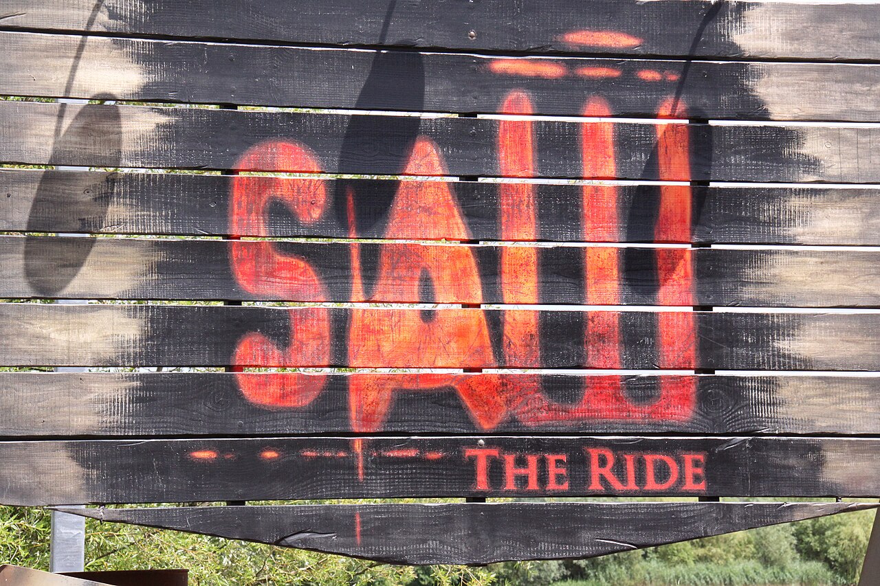 The blood-red Saw The Ride sign on weathered planks at the Thorpe Park entrance