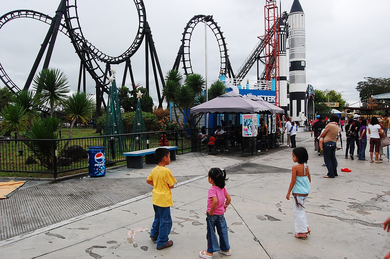 Space Shuttle roller coaster loop and rocket theming seen from the midway at Enchanted Kingdom
