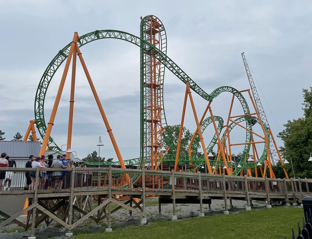 Tantrum roller coaster at Six Flags Darien Lake with green track and orange supports, showing its vertical lift and loop