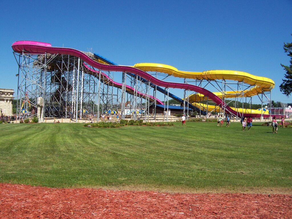 The pink, yellow and blue Triton water slide towering over the lawn at Mt. Olympus Water and Theme Park in Wisconsin Dells