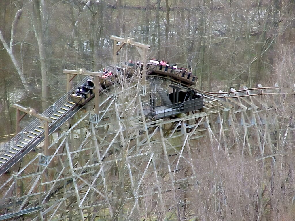 An Adventure Express train cresting a hill above the wooden structure amid bare trees at Paramount's Kings Island, April 2001