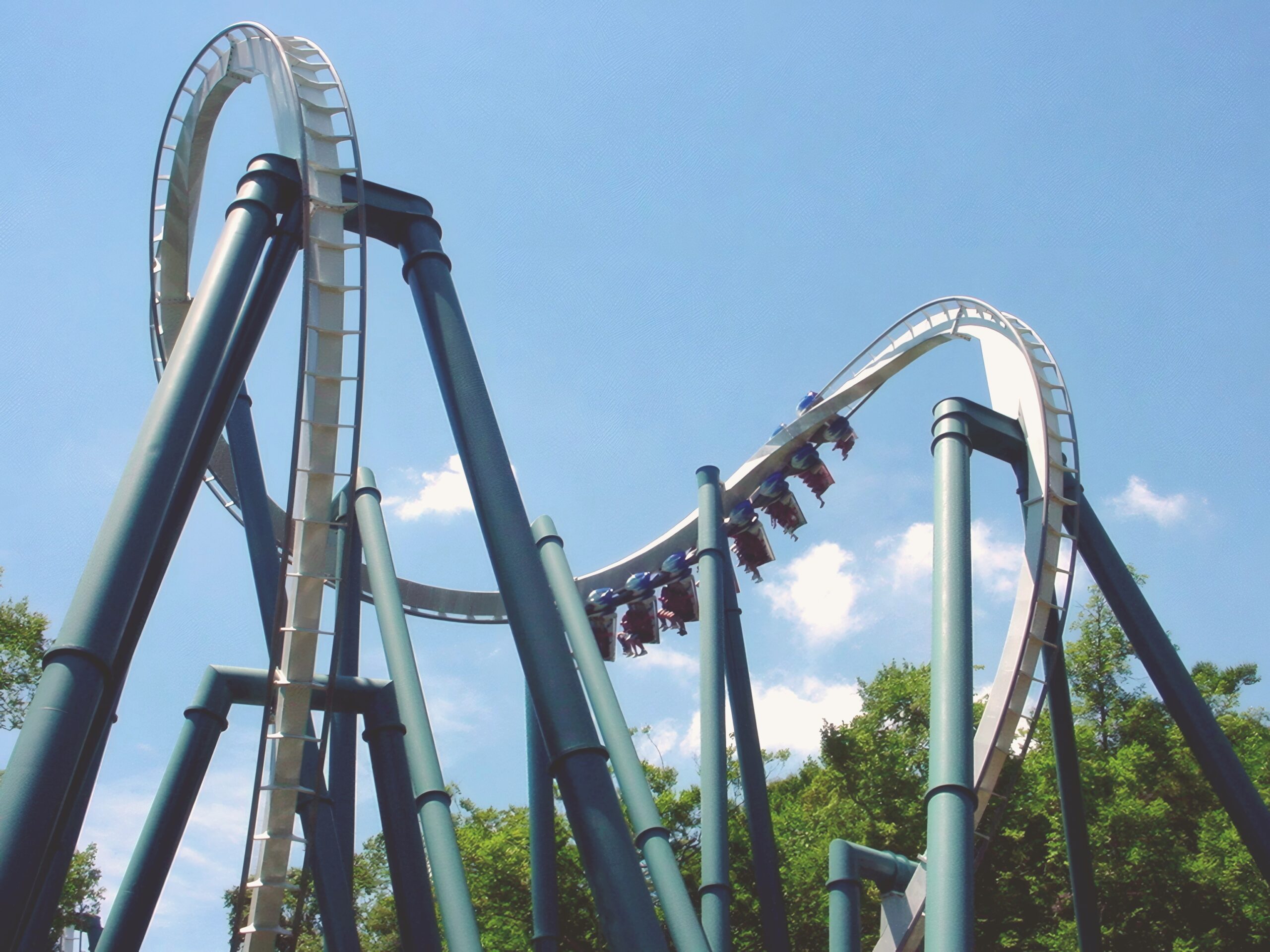 An Alpengeist train twisting through the cobra roll above its teal supports at Busch Gardens Williamsburg