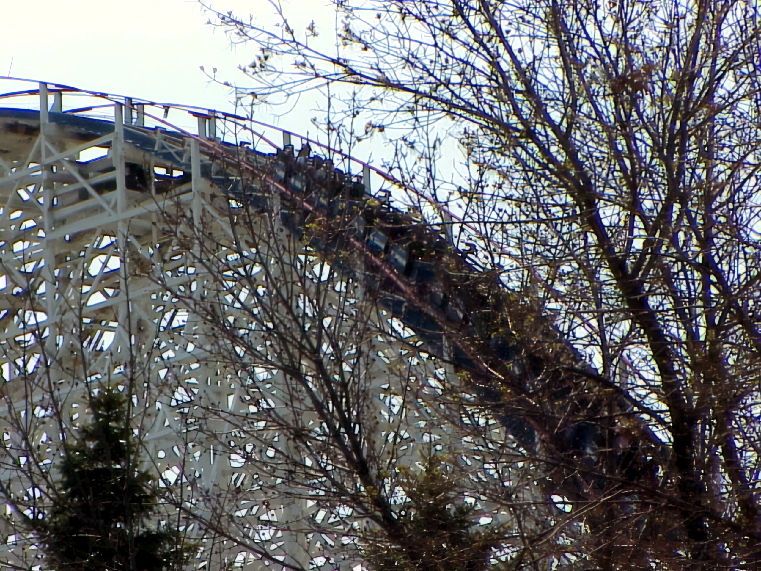 White wooden coaster with blue train seen through bare trees, American Eagle