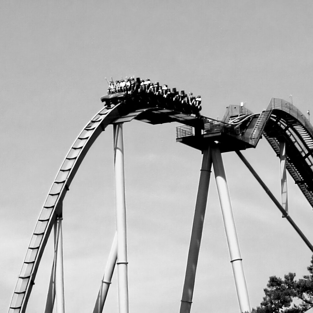 An Apollo's Chariot train over the crest of the lift hill, starting the first drop at Busch Gardens Williamsburg, in black and white