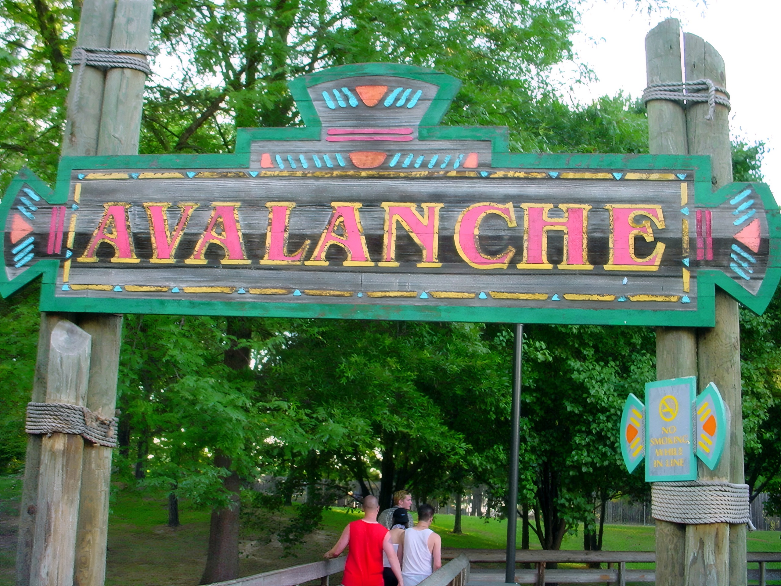 The Avalanche entrance sign among the trees, with guests walking by at Paramount's Kings Dominion, July 2001