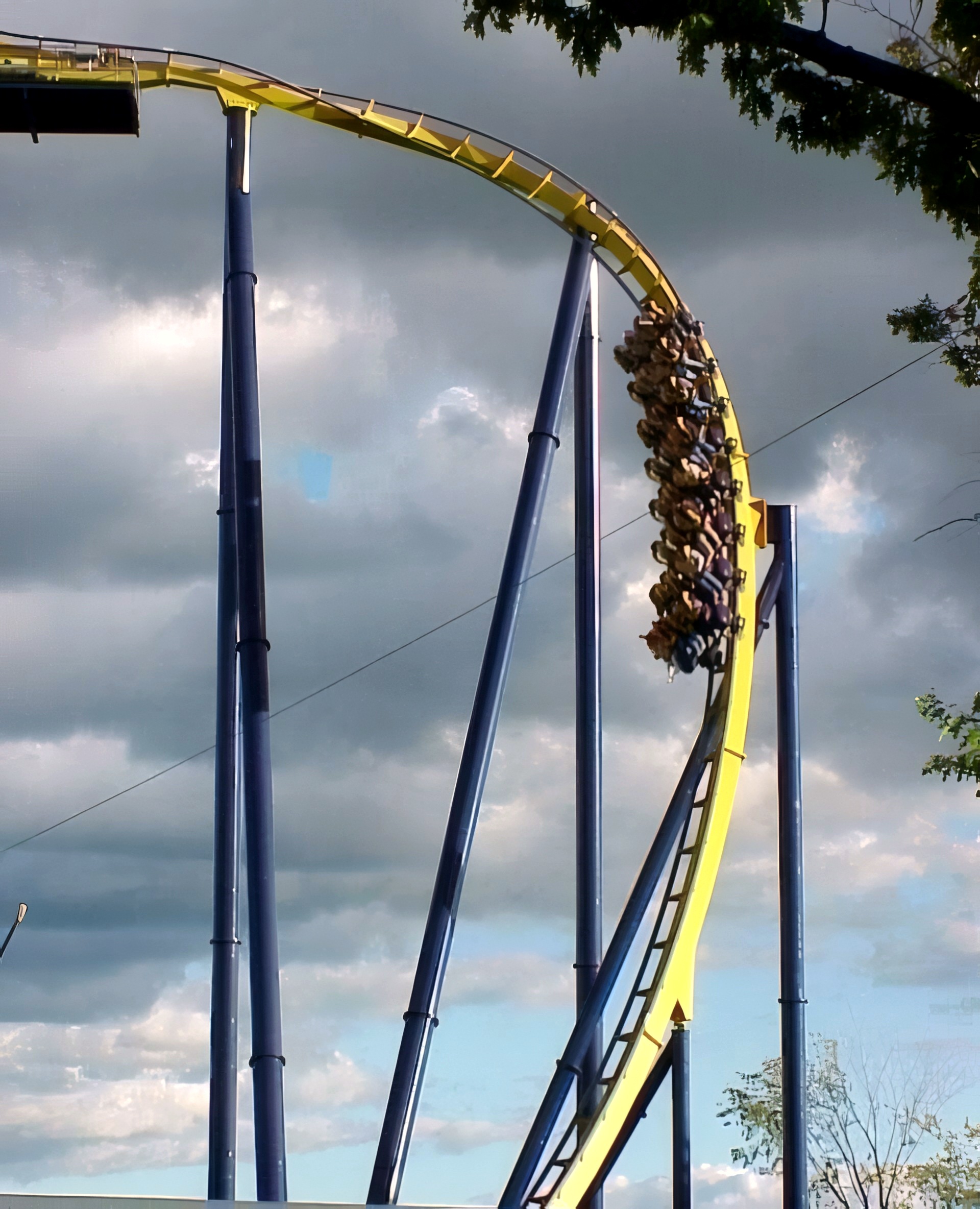 Batman Knight Flight's track against a cloudy sky with a train in the distance at Geauga Lake, May 2000