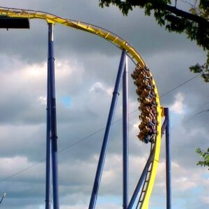 A Batman Knight Flight train hanging on the yellow track against storm clouds at Geauga Lake, dark supports at the right edge