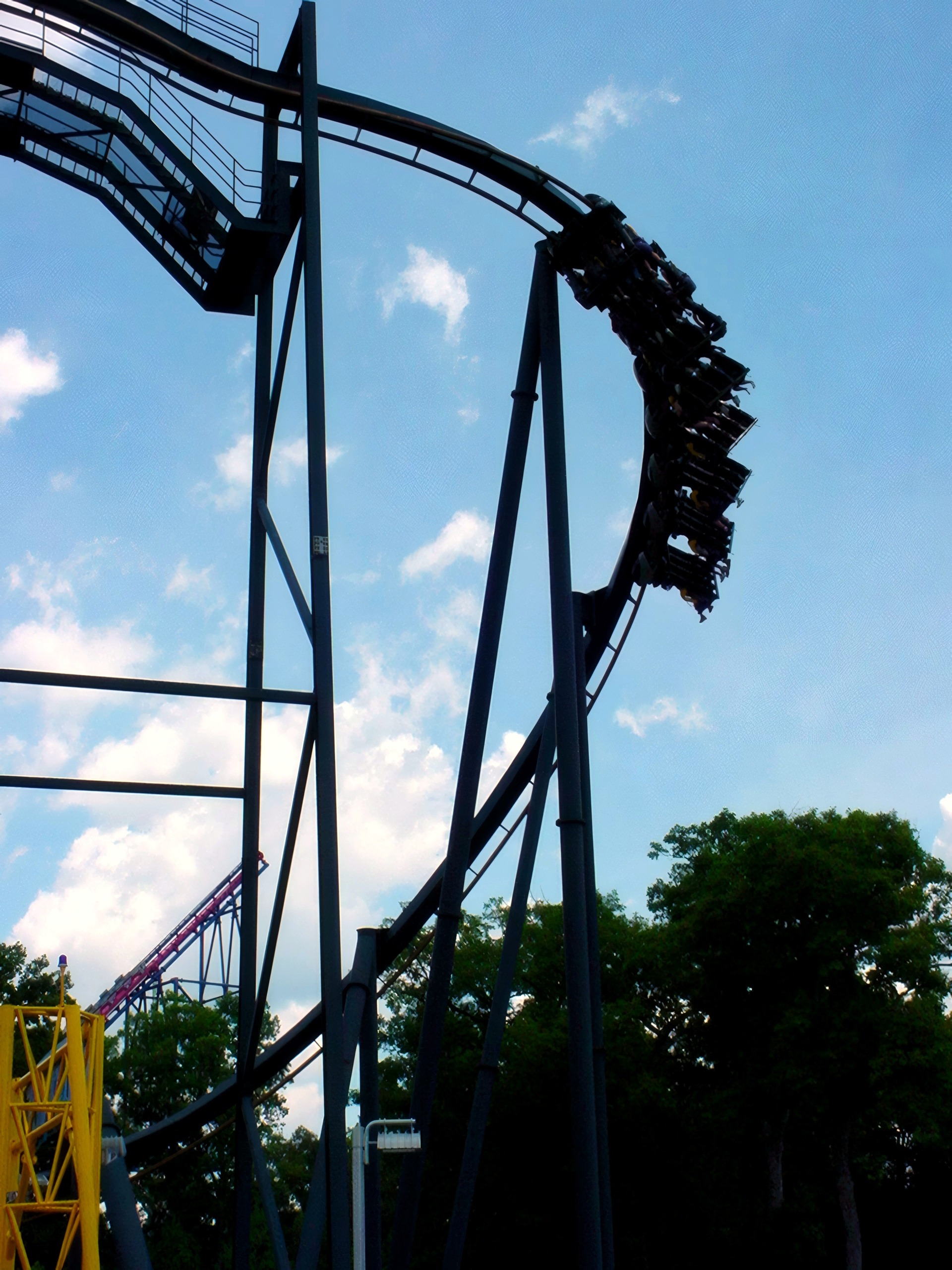 Silhouetted inverted train diving through a loop against sky, Batman: The Ride, July 2001