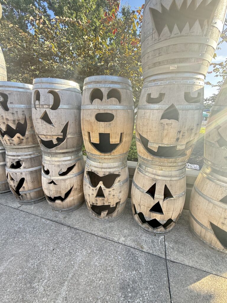 A row of carved jack-o-lantern barrels on the midway in evening sun