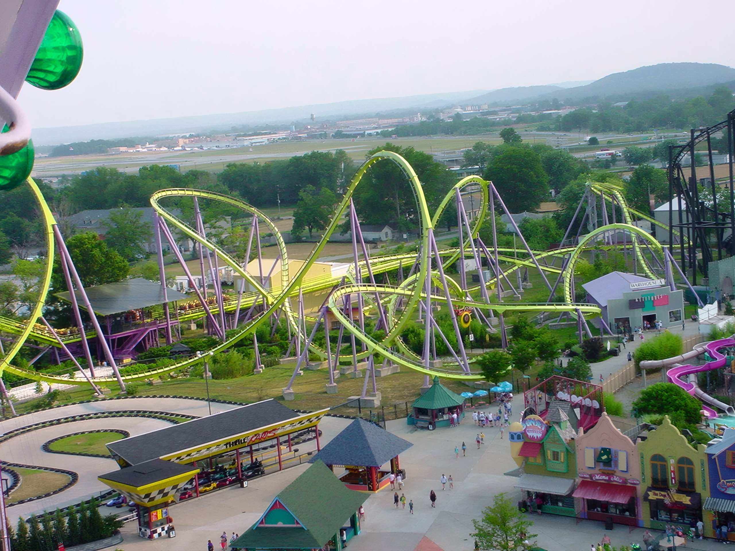 Aerial view of yellow looping steel coaster over midway, Chang, July 2002