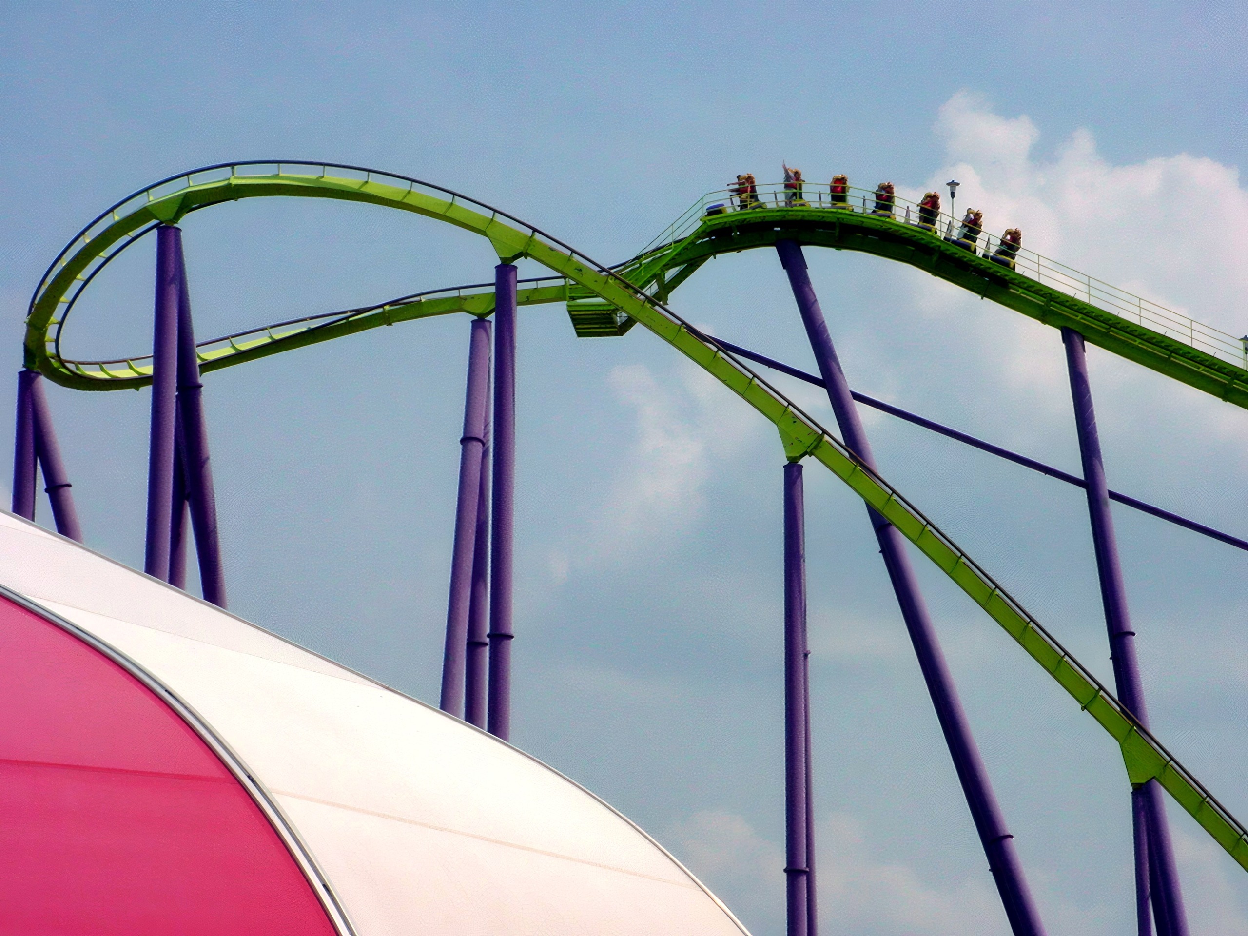 Green steel coaster train cresting hill, purple supports, Chang, July 2002