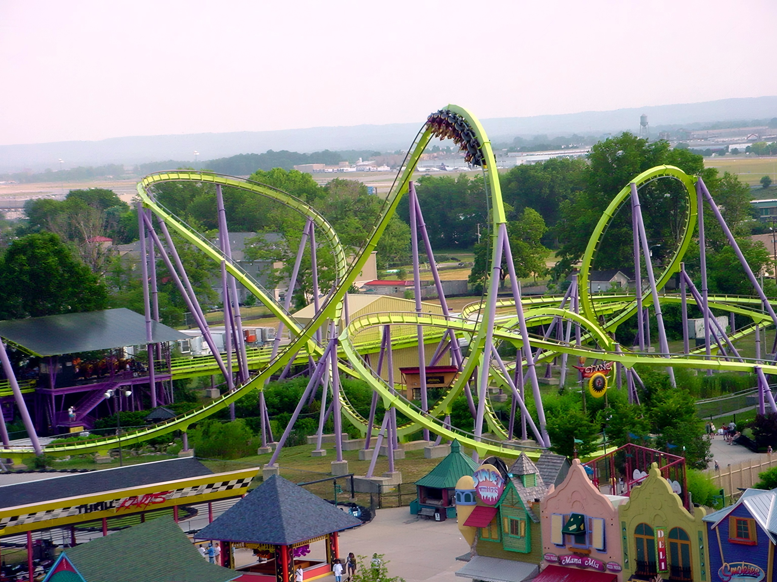 Steel coaster loops above midway shops and trees, Chang, July 2002