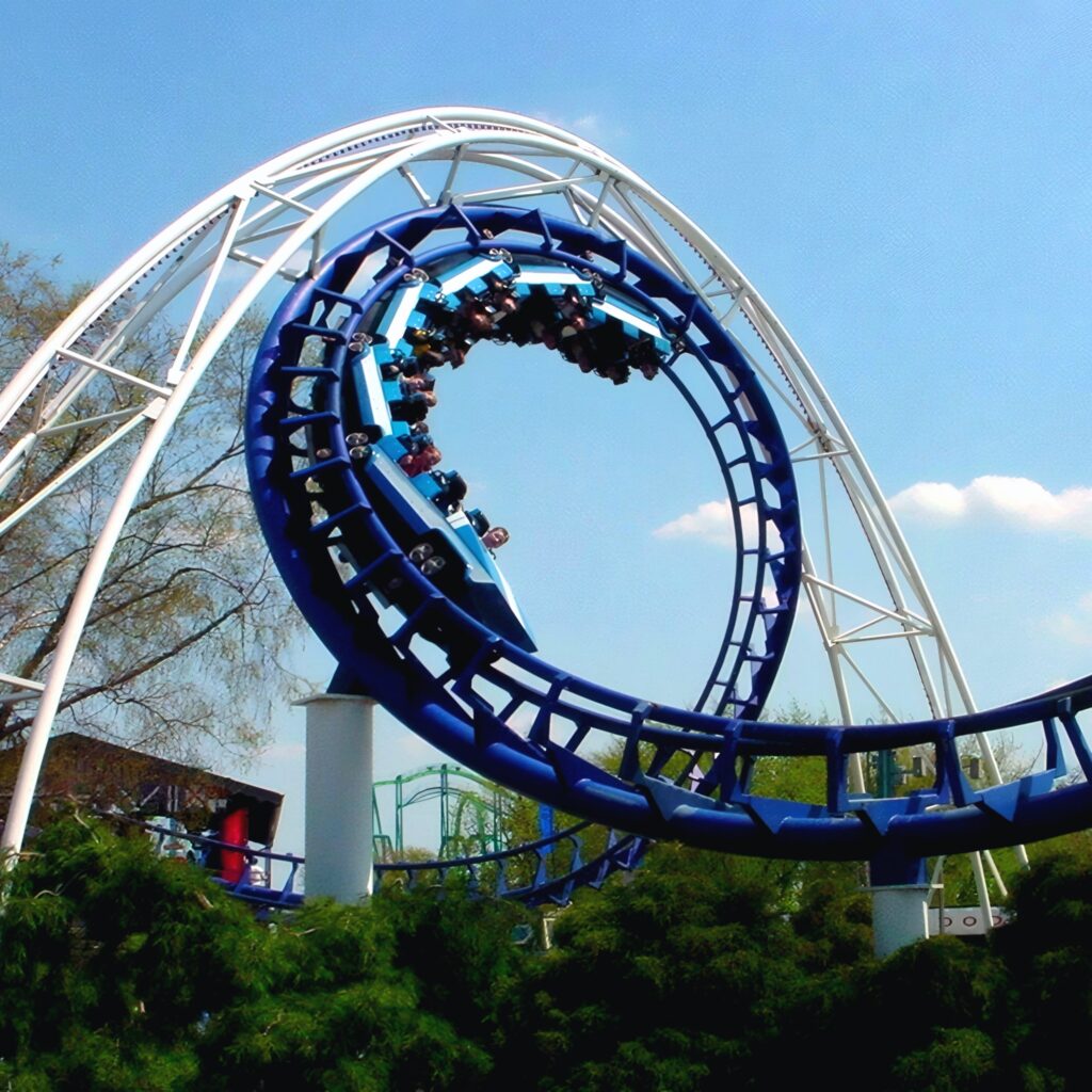 Corkscrew at Cedar Point: a train rolling through the blue corkscrew element above the midway
